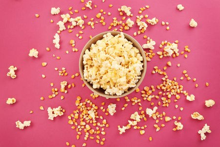 Bowl full of traditional popcorn on pink background