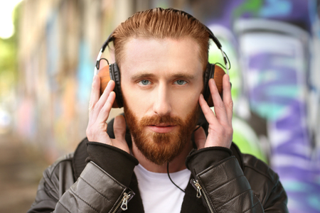 Handsome man in headphones listening to music outdoorsの写真素材