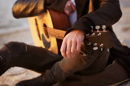Handsome man with guitar on beachの写真素材