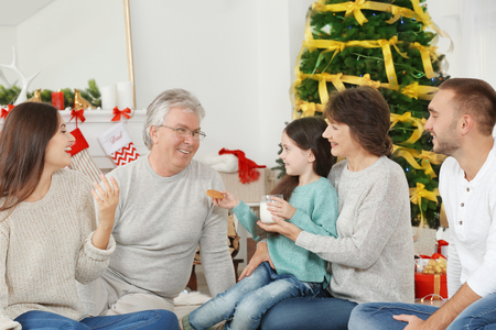 Happy family with cookies and milk in living room decorated for Christmasの写真素材
