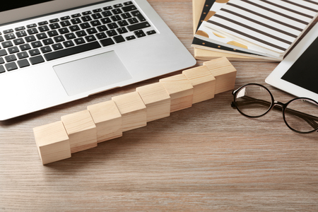 Laptop, copybook and wooden cubes on color backgroundの写真素材