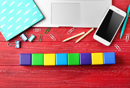 Laptop, copybook and wooden cubes on color backgroundの写真素材