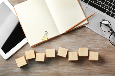 Tablet, copybook and wooden cubes on color backgroundの写真素材