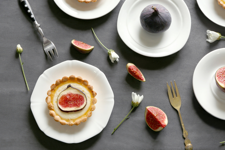 Plates with tasty fig cakes and fresh fruits on grey background, top viewの写真素材