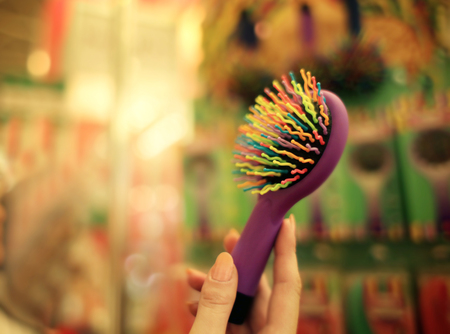 Female hand holding colourful barber comb in cosmetic storeの写真素材