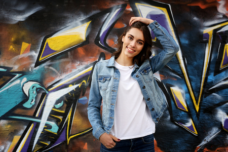 Pretty young woman in blank t-shirt against graffiti wallの写真素材