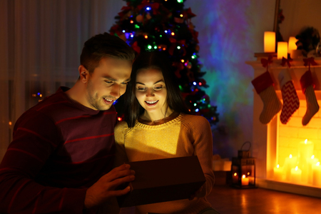 Young couple opening Christmas present in living roomの写真素材
