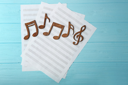 Music notes and sheets of paper on color wooden backgroundの写真素材
