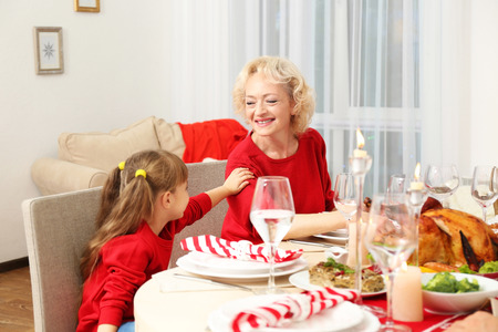 Little girl and her grandmother sitting at table during Thanksgiving dinnerの写真素材