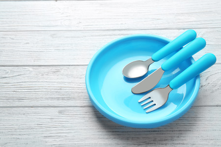 Bright baby tableware on white wooden backgroundの写真素材