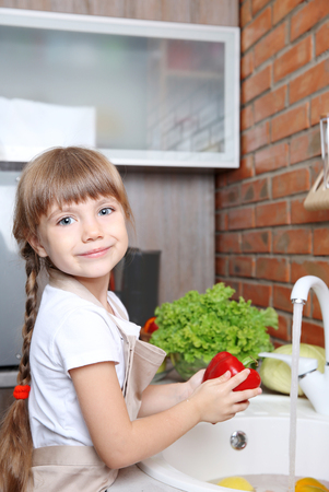 Small girl washing vegetables in kitchenの写真素材
