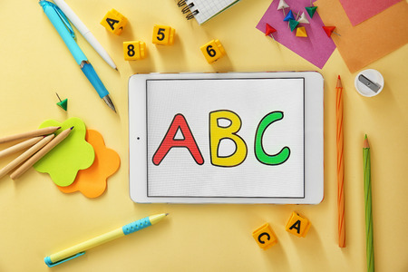 Colourful stationery and tablet on beige backgroundの写真素材