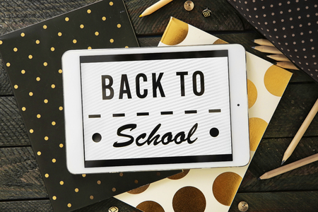 Colourful stationery and tablet with BACK TO SCHOOL phrase on black wooden backgroundの写真素材