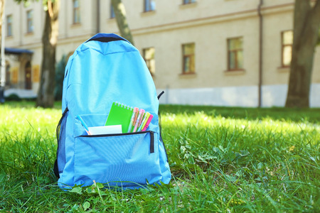 School backpack with accessories on green grassの写真素材