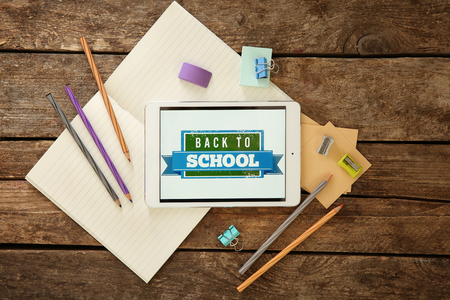 Colourful stationery and tablet with BACK TO SCHOOL phrase on wooden backgroundの写真素材