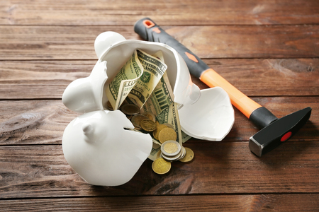 Broken piggy bank with money on wooden tableの写真素材