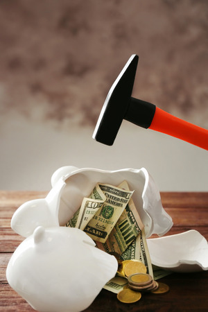 Broken piggy bank with money on wooden tableの写真素材