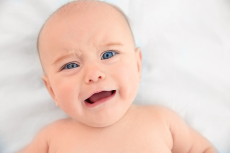 Cute baby lying on white bed sheet, close up viewの写真素材