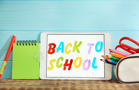 Tablet with text BACK TO SCHOOL and stationery on tableの写真素材