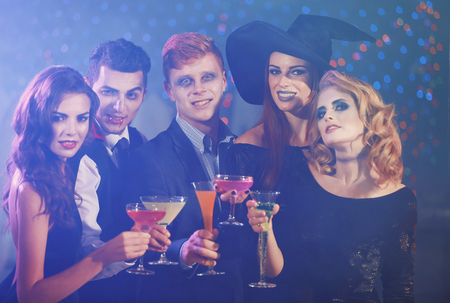 Young people in costumes having fun at Halloween partyの写真素材