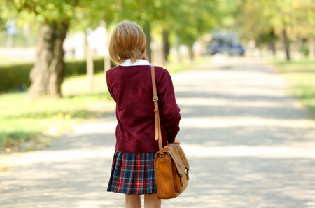 Schoolgirl walking along alley in green parkの写真素材
