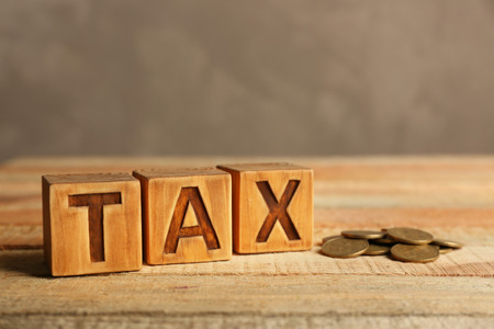 Tax concept with cubes and coins on light backgroundの写真素材