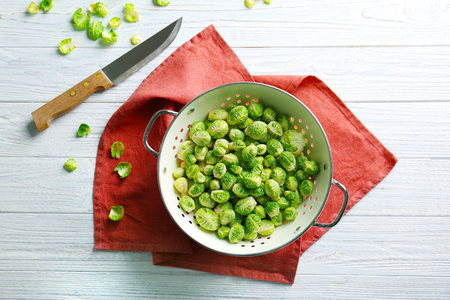 Brussels sprouts in colander with knife on tableの写真素材