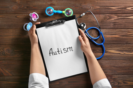 Doctor holding clipboard on wooden table. Autism conceptの写真素材