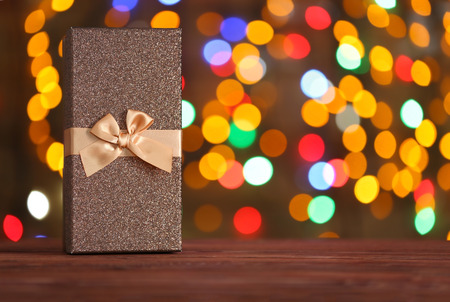 Box with Christmas present on wooden surface against defocused lightsの写真素材