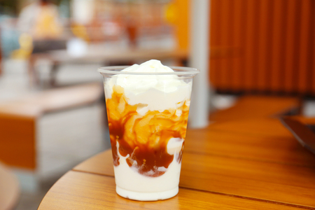 Plastic cup of delicious cool dessert on wooden tableの写真素材