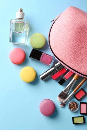 Makeup products with cosmetic bag and macaroons on blue backgroundの写真素材