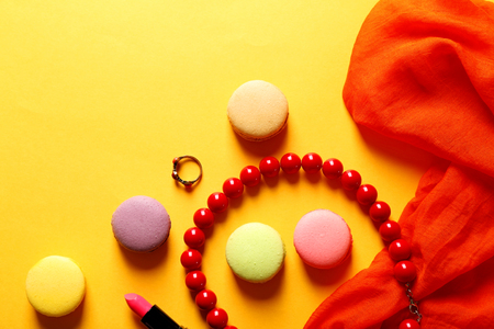 Makeup products, accessories and macaroons on yellow backgroundの写真素材