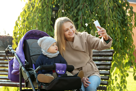 Young woman with cute baby taking selfie outdoorsの写真素材