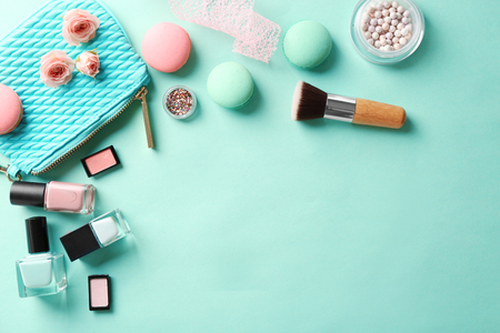 Makeup products with cosmetic bag and macaroons on color backgroundの写真素材