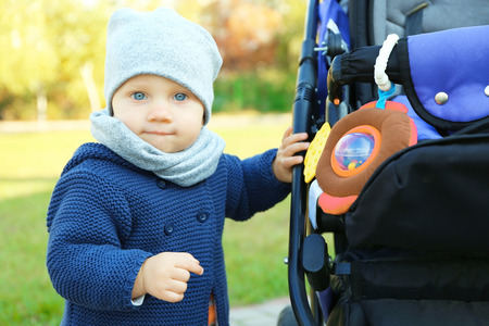 Cute little baby near stroller outdoors, close up view