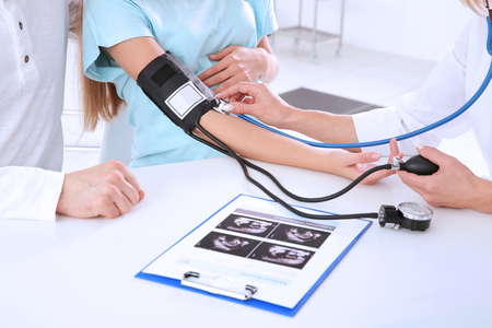 Doctor measuring blood pressure of pregnant womanの写真素材