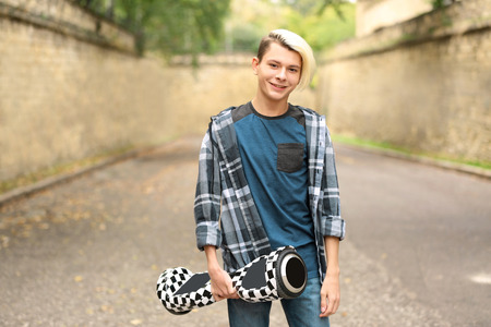 Teenager boy with hoverboard outdoors