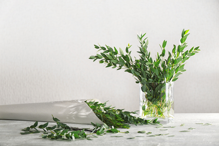 Green eucalyptus branches in vase and paper wrap on tableの写真素材
