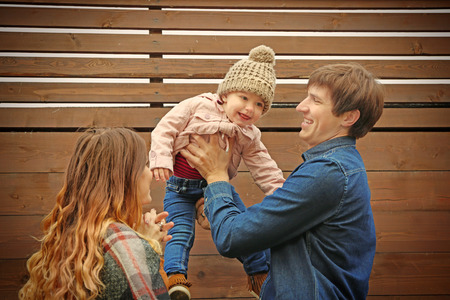 Happy young family near wooden fence in autumn day
