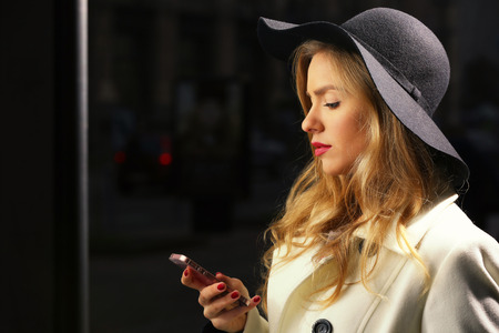 Young woman using mobile phone in street at evening time