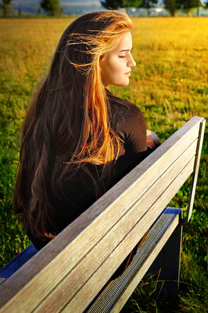 Young woman sitting on bench in parkの写真素材