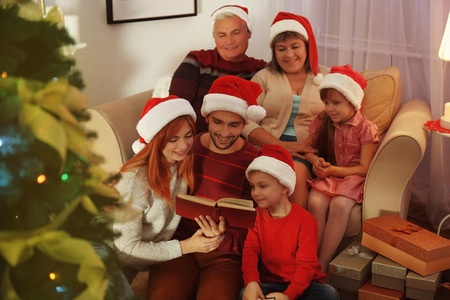 Family reading book in living room decorated for Christmasの写真素材
