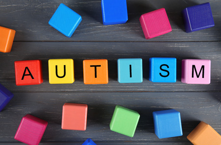 Wooden cubes with word AUTISM on wooden background