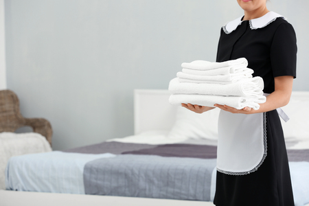 Chambermaid holding pile of clean towels in the roomの写真素材