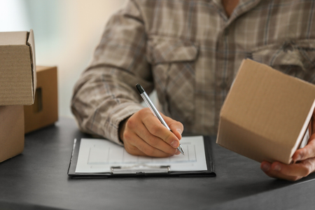 Courier making notes in delivery receipt at table