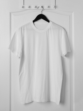 Blank white t-shirt hanging on door