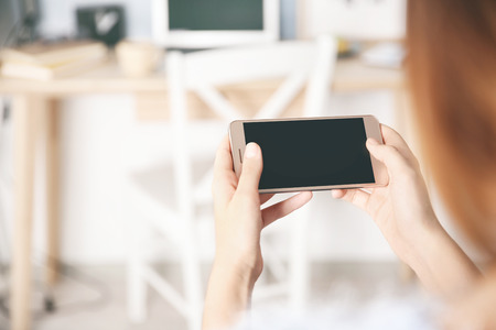 Woman holding modern cellphone at home