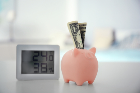 Savings concept. Piggy bank and electronic thermometer on tableの写真素材