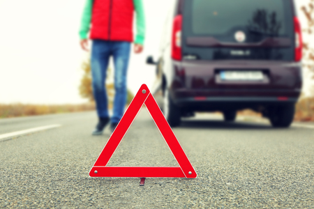 Traffic warning sign on road with car and driver on backgroundの写真素材