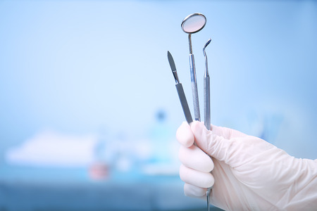 Dentist holding set of medical tools on blurred backgroundの写真素材
